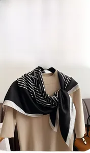 Detailed close-up of a black and white geometric silk scarf draped on a beige sweater
