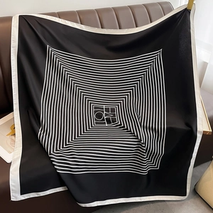 Detailed view of large silk scarf featuring geometric radial lines on a leather sofa