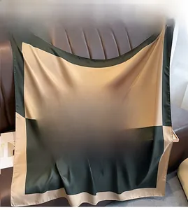 Detail of color-block twill silk scarf in dark green and champagne on leather texture
