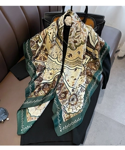 Detail of bohemian silk scarf with paisley pattern draped over a classic black blazer