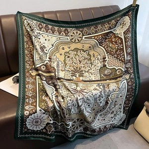 Forest green and ochre silk scarf with tree of life pattern on leather sofa