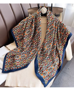 Detailed close-up of large floral silk scarf with dark blue border and silky texture