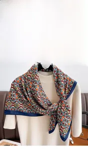 Close-up of floral twill silk scarf with navy blue satin borders and vibrant patterns
