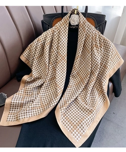 Détail d'une écharpe à motif pied-de-poule marron avec bord en satin sur cuir
