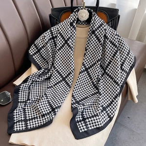 Détail d'une écharpe légère à motif pied-de-poule noir et blanc sur un pull en maille