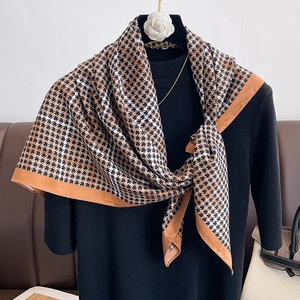 Détail du foulard en soie avec motif pied-de-poule classique et bordure orange