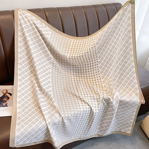 Detail of houndstooth silk scarf with geometric square pattern on leather sofa