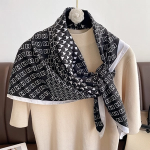 Detail of black and white houndstooth silk scarf on beige knitwear with camellia hanger