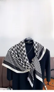 Detail of classic black and white houndstooth silk scarf with camellia flower brooch