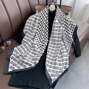 Detail of houndstooth silk scarf with geometric chain logo and grey border on leather