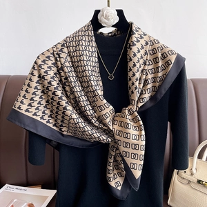 Detail of silk-textured houndstooth scarf with gold geometric patterns on a black knit top