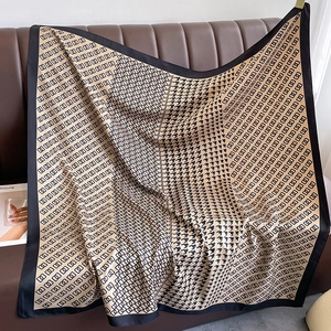 Detail of classic houndstooth and geometric chain silk scarf draped on leather sofa