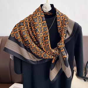 Close-up of vintage floral silk scarf with vibrant orange geometric patterns and glossy texture