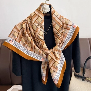 Detail of elegant geometric silk scarf tied on mannequin neck in orange and brown tones
