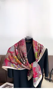 Detail of burgundy floral silk scarf draped over a black turtleneck sweater and bag