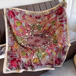 Detail of artistic floral twill scarf with vintage red patterns on a leather sofa