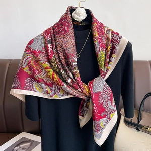 Detailed view of red twill silk scarf with floral patterns on a vintage leather background