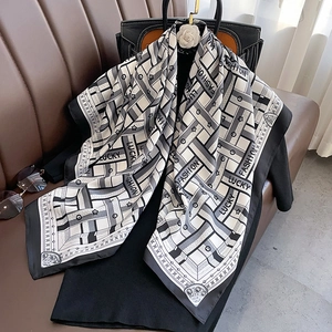 Close-up of geometric silk scarf with Lucky and Fashion prints on a leather seat