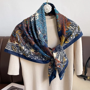 Retro paisley twill silk scarf in navy and orange draped over a beige knit top
