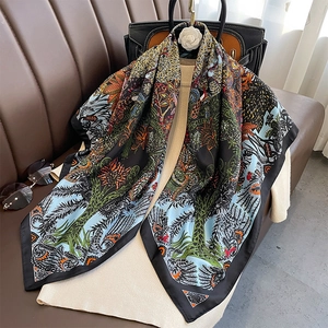 Detail view of a 90cm square silk scarf with tropical flora print on a beige sweater