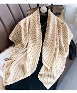 Detail of elegant cream twill silk scarf with brown radial lines on a black knit top