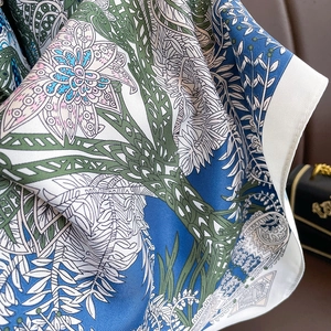 Detail of silk twill scarf showing peacock blue floral patterns and fabric texture