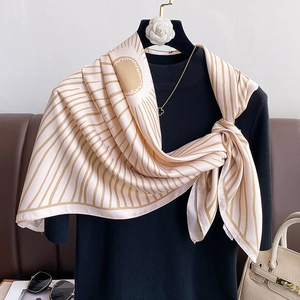 Elegant silk scarf with sun and stripe patterns styled on a black sweater hanger