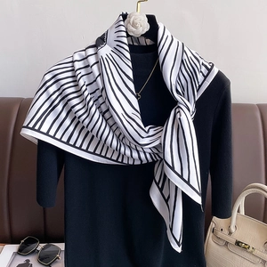 Close-up of black and white striped silk scarf with abstract patterns on a knit top