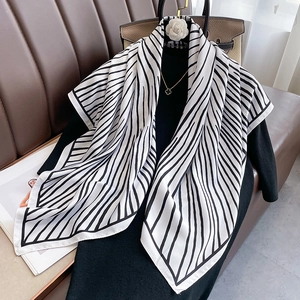 Elegant black and white striped twill silk scarf styled with a camellia brooch and bag