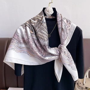 Close-up of elegant 90cm printed silk scarf with vintage patterns on a black sweater