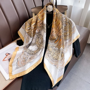Detail of silk satin scarf with baroque pattern draped over black outfit and leather bag
