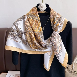 90cm square silk scarf with gold and ivory geometric print tied over a black sweater