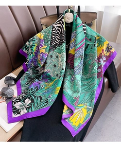 Close-up of vibrant floral and zebra print silk scarf on a luxury leather surface