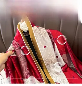 Detailed view of red floral silk shawl showing satin texture and golden hem finishing