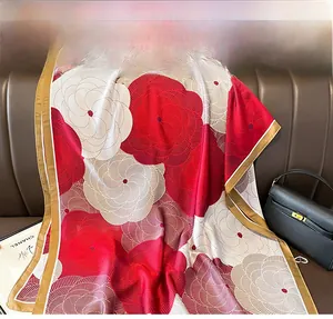 Detailed close-up of a floral silk scarf with red and white patterns on a leather sofa