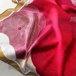 Floral print silk scarf with vibrant red and gold patterns showing soft draped texture