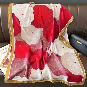 Floral faux silk scarf in red and cream displayed on a leather sofa for sun protection