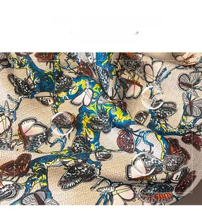 Détail d'une écharpe en soie avec imprimés papillons colorés et motifs géométriques