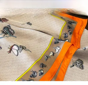 Gros plan des coutures précises sur le foulard en soie orange à motif floral