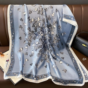 Détail d'une écharpe bleue satinée avec imprimés papillons et texture soyeuse élégante