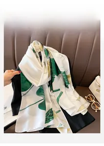Detail of silk scarf with green leaf pattern draped over a black suit jacket