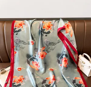 Detail of grey-green vintage floral scarf with silk texture draped on a leather sofa