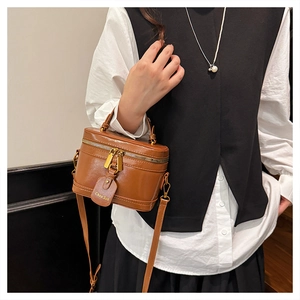Close-up of vintage brown leather cylinder box bag with gold zipper and stylish tag