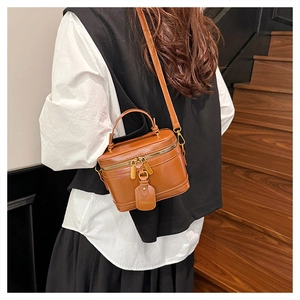 Model showing retro brown leather box bag with handle and strap on stairs
