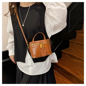 Detail of vintage brown box bag with gold hardware and logo tag on leather strap