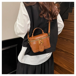 Close-up of vintage brown leather box bag featuring top handle and metallic brand tag