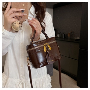 Close-up of a dark brown glossy leather box bag with metal zipper and handle details