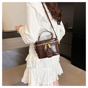 Detail of dark brown vintage box bag with gold double zippers and elegant leather tag