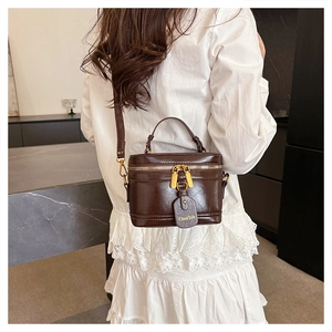 Detail of vintage coffee leather box bag with gold zipper and branded tag accessory