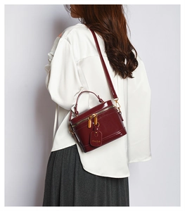 Chic burgundy box bag in glossy finish worn by model as a stylish crossbody accessory